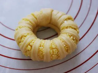 椰蓉奶香面包圈,拿起两头往中间合拢，把其中一头卷紧些，插入另一头捏紧捏实。