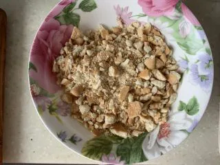 芒果慕斯蛋糕,饼干捏碎,或者使用擀面杖,变成饼干末,最好用奥利奥饼干(去掉夹心)、消化饼干等,因为没法出门采购,用了姥姥的青食钙 奶 饼干,这种饼干用擀面杖不好使,纯手工捏碎,建议捏的再碎一点,吃起来口感会更细腻,加入融化的黄油,搅拌均匀。准备6寸活底模具,模具底下垫一张等大的油纸,将拌均匀的饼干放入,压实,放入冰箱冷藏备用。
