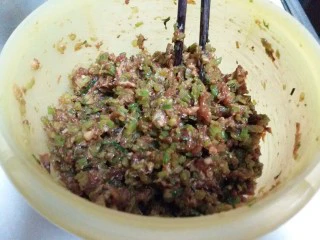 南瓜芹菜肉包子,将芹菜、猪肉倒入盆里,依次放入玉米油、盐、蚝油、海鲜酱油、绵白糖和炒好的葱姜甜面酱用筷子顺一个方向搅动上劲。