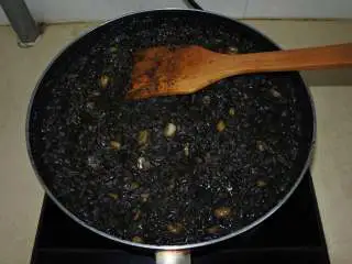 煎南美虾球配意式墨汁海鲜烩饭,把米煮粘稠，但不要收干汤汁，稍微湿润一点，取出香叶