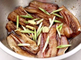 日式柠香烤鳗鱼,撒上葱姜丝拌匀腌制1小时。