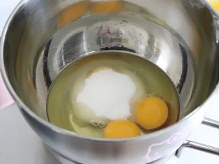 橙味甜甜圈蛋糕，在家就可复刻的经典美味,全蛋加入细砂糖，放置到50度左右的温水中，让蛋温稍微升高，并用电动打蛋器打发。