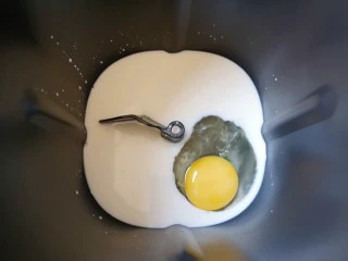 麦片芝麻小餐包,面包机桶内加入牛奶,打入一个鸡蛋。