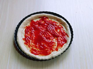 披萨新吃法~奥尔良鸡丁披萨,取一块面团擀成与披萨盘一样大的披萨皮,再用叉出洞洞,涂抹上番茄酱。