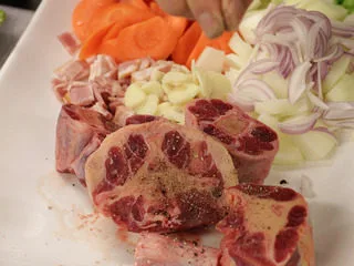 番茄红酒烩牛尾,洋葱，西芹，胡萝卜，大番茄切成块状，培埂和蒜切片。并在牛尾上撒上盐和胡椒