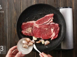 香汁煎牛排，在家也能做出米其林大厨的味道,牛排入锅，加入蒜瓣