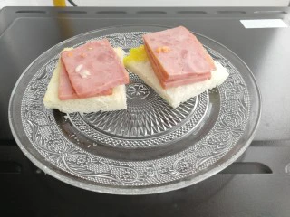 快手早餐&吐司鸡蛋烤火腿&小米粥,烤5分钟后可以把火土和切的四方吐司片拿出来（否则鸡蛋被盖住烤不熟）。