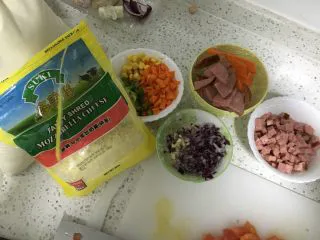 培根芝士焗饭,准备好所需食材，胡萝卜、青椒切丁，洋葱、蒜切小粒。火腿切丁。