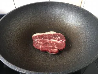 红酒黑胡椒牛排,大火置锅,锅烧热,放入少许的橄榄油润一下锅,放入板腱牛排,中火煎3分钟。煎的时候不要翻动板腱牛排,避免牛排汁水流失。