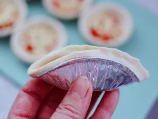 草莓芝士酥～蛋挞皮版,把蛋挞皮对折一下，然后从蛋挞的一边开始捏起。