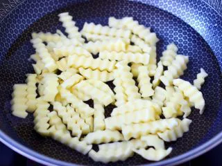 炸锅版狼牙薯条,锅中倒入适量的清水,放入浸泡过的土豆条。