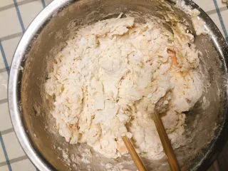 杂蔬沙拉面包,多次少量加入温水，搅拌成面块，搅拌后底部剩有少许面粉为宜。