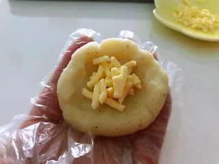 土豆爆浆芝士,用手压平,中间放入芝士,包裹起来,成圆形。