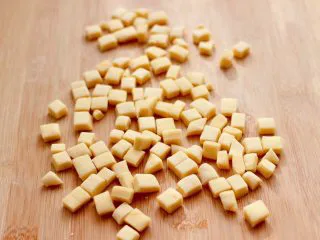 奶香小花朵馒头,把边角料重新揉匀后，再次擀成薄片后，用刀切成小豆豆，也可以继续用模具压成小花朵。