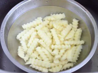 炸锅版狼牙薯条,把切好的土豆条,放入盆中用清水浸泡一下淀粉。