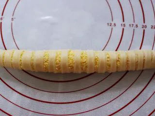 椰蓉奶香面包圈,切好后从侧面卷起，卷成长筒状底边放在下面压住，防止发酵时胀开。