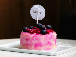 火龙果渐变蛋糕(宝宝辅食),最后在上面铺上一些火龙果肉和蓝莓,无糖的宝宝辅食蛋糕就完成了。