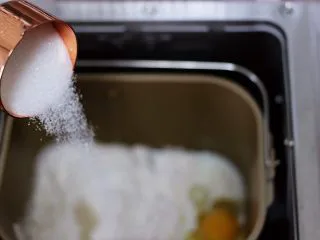 椰蓉奶香面包圈,把牛奶加入面包桶，再加入盐和甘汁园双碳白砂糖，（糖与盐对角放）再加入鸡蛋(鸡蛋重量约50g左右)最后加入高筋面粉和低筋面粉，面粉中间挖个洞，放入酵母粉，再用旁边的面粉把酵母粉盖起来。