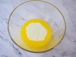 酸奶蛋糕(黄油版),将黄油隔水融化成液体,再加入酸奶,用手动打蛋器搅拌均匀