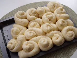 儿时的味道～脆皮蜂蜜小面包,模具中刷上少许的食用油，放入面包胚，放入烤箱中发酵至两倍大，底部放一盆热水，表面刷一层蜂蜜水，撒上白芝麻。