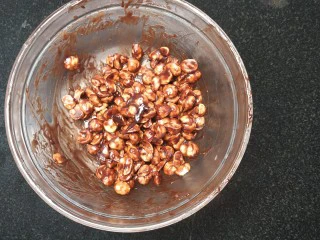 网红夏威夷果仁可可脆脆巧克力片 香港珍妮聪明小熊夏威夷果仁巧克力脆脆,18.然后我们来制作材料B的坚果仁部分 无盐黄油4克＋枫糖浆或者蜂蜜6克＋巧克力5克放入无油无水的别容器里，隔水加热至全部融化，一边融化一边用硅胶刮刀搅拌均匀； 然后趁热加入熟的奶油味夏威夷果仁1/2颗粒的30克；