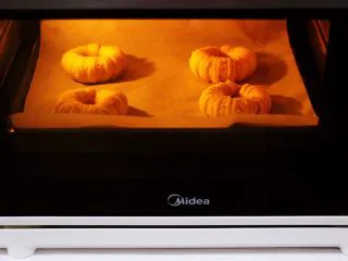 椰蓉奶香面包圈,发酵至两倍大时表面刷稀蛋液，放入上火175度下火170度的烤箱中层，烤15分钟即可。