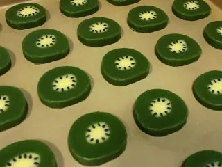 猕猴桃造型饼干,用牙签沾水后，把黑芝麻往饼干上粘。