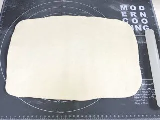 椒盐五香千层饼,按压排气揉圆，稍稍松驰，将面团擀开，擀成长方形薄片。