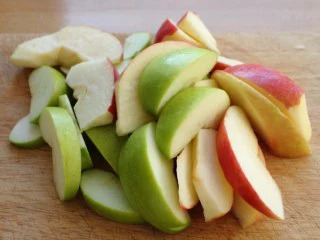 苹果柠香烤鸡腿,在烤的同时，我们将苹果洗净、去核、切成船形，挤点柠檬汁。 注：这里柠檬汁的作用是防氧化，增味。 