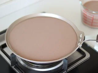 巧克力毛巾卷,准备制作饼皮,首先需要准备湿抹布,用于冷却锅底。之后平底锅倒入面糊,摇匀平铺的状态,小火烙饼。