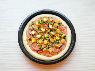 火腿彩蔬披萨,均匀的撒上黄瓜丁、胡萝卜丁和熟玉米粒。
