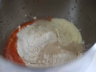 胡萝卜热狗面包,做营养美味早餐,厨师机面缸中,放入液体,加入粉类,放入干酵母。预留的水分也暂时不放,黄油不放。