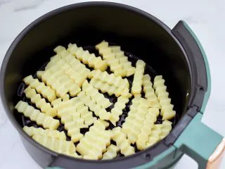 炸锅版狼牙薯条,空气炸锅提前200度预热5分钟后,把抹好的土豆条放入炸篮里。