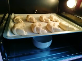 燕麦全麦羊角包,烤箱调至“发酵”功能,放一碗热水,放入羊角包生胚发酵30分钟。