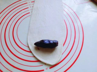 #甜味#毛毛虫豆沙面包,取一块松弛好的面团，用擀面杖擀成长舌状，再把豆沙馅放上去。(也可以把豆沙馅压扁，和面团一起擀成长舌状，根据个人喜欢来。)