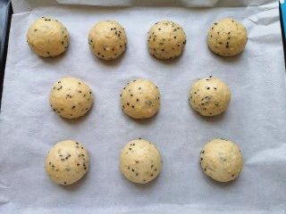 麦片芝麻小餐包,烤盘里铺上油纸,将面包面团滚圆放在油纸上。