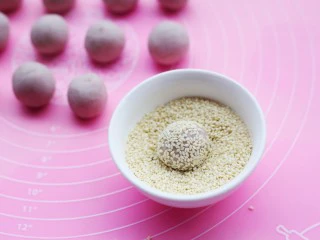 奶香芋泥芝麻球,每一个圆球表面裹上白芝麻,将芝麻往里按一按,然后放入烤盘中。