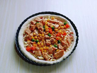 披萨新吃法~奥尔良鸡丁披萨,再把做好的奥尔良鸡肉均匀的铺在披萨皮上面。