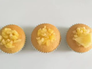 果味长崎纸杯蛋糕,最后把凤梨果肉丁和果肉片取适量放在蛋糕上,摆上薄荷叶装饰即成!