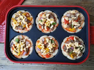 至尊牛肉小披萨,铺上一层炒好的牛肉和配菜,根据个人口味撒上适量的奶酪碎。