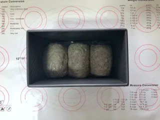 黑芝麻吐司(一次发酵）,收口朝下码入吐司盒中，盖上保鲜膜室温下进行发酵。