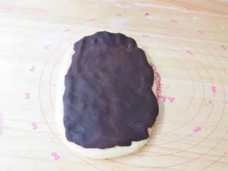 豆沙吐司面包,取一份面团擀成牛舌状，豆沙馅借助保鲜膜擀开放在面团上