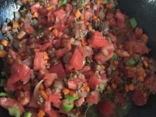 番茄牛肉意大利面,烧热锅加适量橄榄油,大火爆香香葱和蒜泥,加入洋葱翻炒爆香,加入牛肉末翻炒到变色,加胡萝卜,西红柿,青椒一块翻炒均匀,在加调料,盐,生抽,黑胡椒粉,加入浓缩汤宝,番茄酱,加适量水煮。,中火煮到汤汁变成红色,大火收汁。