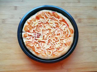 百变水果 水果披萨,烤制好的饼皮从烤箱里取出，抹上一层番茄酱，撒上一些马苏里拉芝士。