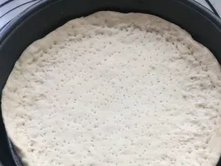 意式烤肠披萨,擀成圆形饼坯，放入披萨烤盘，四周略高，用叉子叉出均匀的孔，避免受热膨胀鼓起。