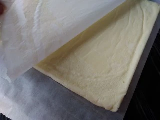 圣诞树根蛋糕,烤好的蛋糕立即取出,晾三分钟后倒扣在另一张干净的油纸上,趁热撕去底部的油纸,放凉