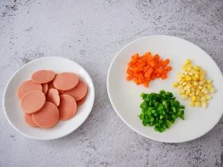 杂蔬火腿肠披萨,把玉米粒洗净备用,胡萝卜去皮洗净切丁,青椒洗净切丁,火腿肠切片备用