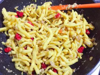 草莓麦片沙琪玛,倒入炸好的面，并加入麦片、黑白芝麻和草莓干搅拌混合均匀