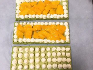 抹茶芒果裸蛋糕,蛋糕分成三份，每一份四周挤入奶油霜，中间放芒果肉，一块挤入奶油霜。