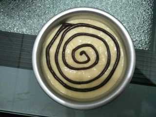 拉花半熟芝士蛋糕,蛋糕糊放入模具中震出汽泡，用巧克力画一个圈。